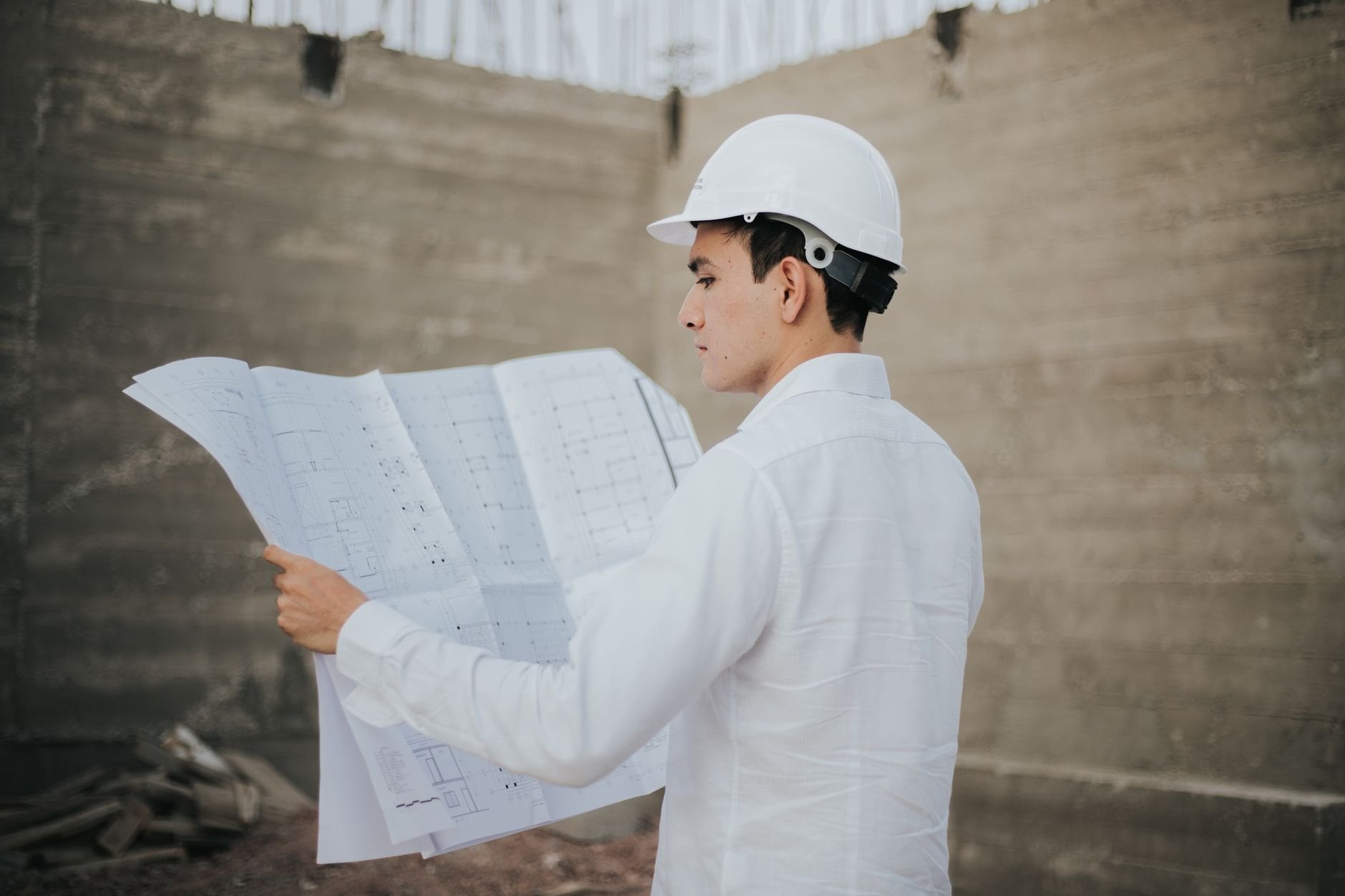 Architect examining blueprints at a construction site, reviewing project details.